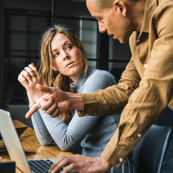 Man explaining something to a woman at a desk with a laptop, reflecting the collaborative approach of Prime Vitality's wellness consultations and personalized care services.