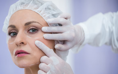 Woman receiving facial treatment with a professional applying product, showcasing the expertise in aesthetic procedures at Prime Vitality Care.